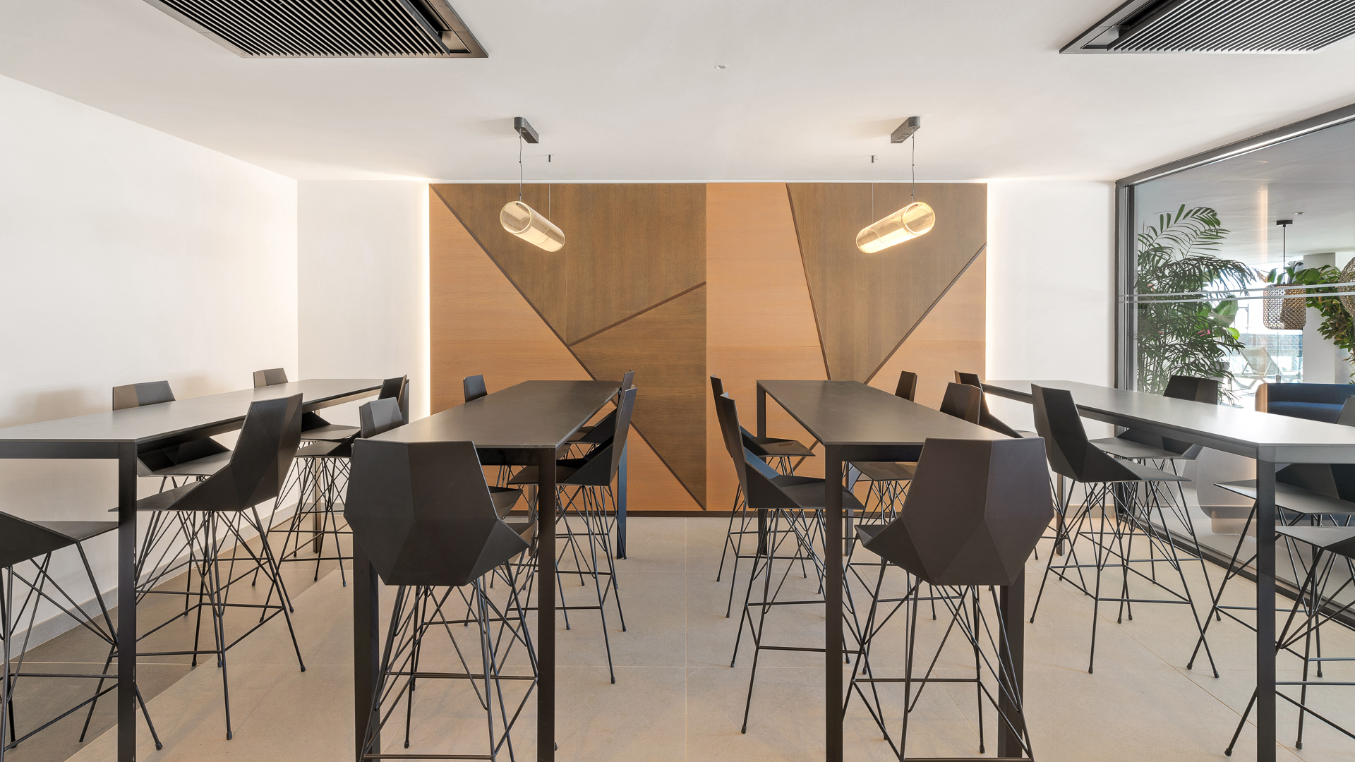 Área de coworking con mesas altas para compartir en zona común.