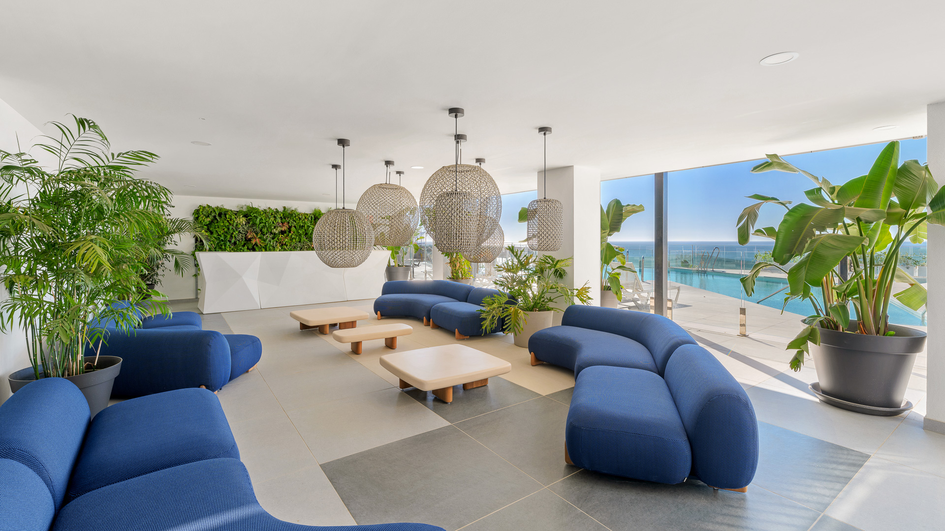 Área lounge de coworking con sofás, plantas decorativas y vistas al exterior.