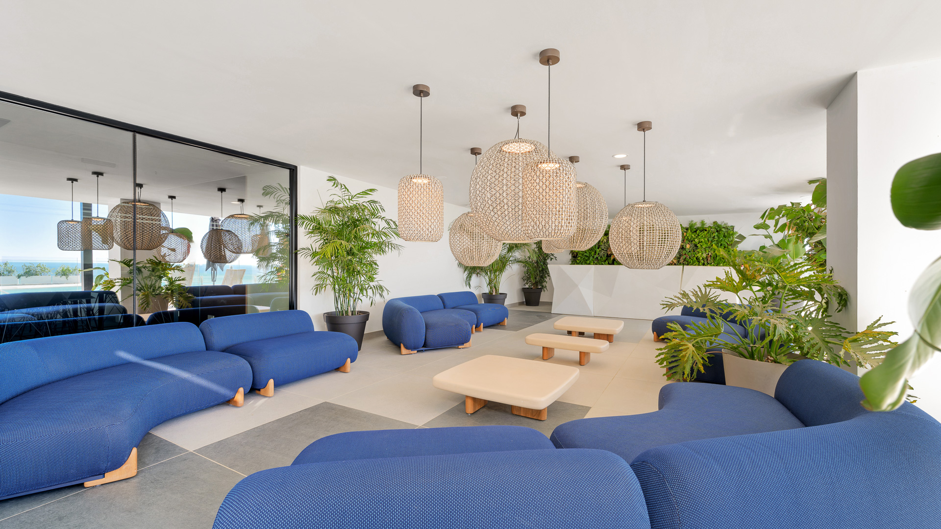 Lounge de coworking con sofás, iluminación decorativa y elementos vegetales.