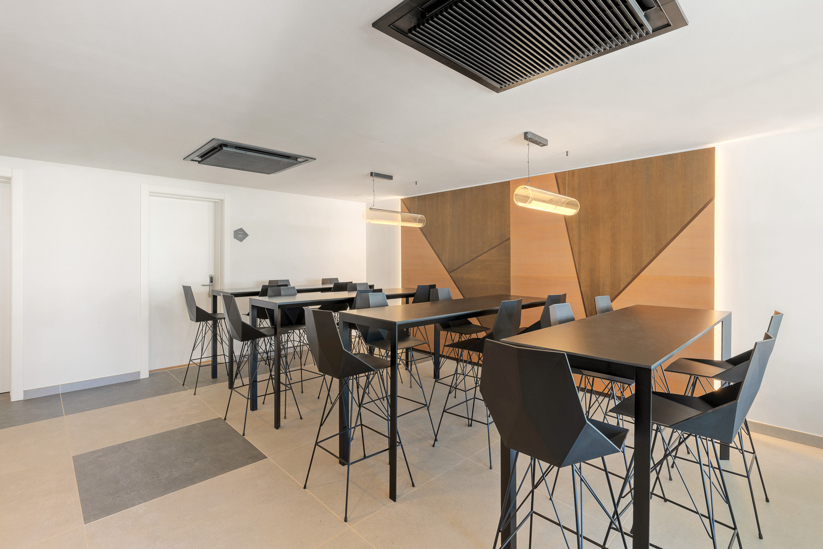 Sala de coworking con mesas de trabajo, asientos modernos y paneles decorativos de madera.