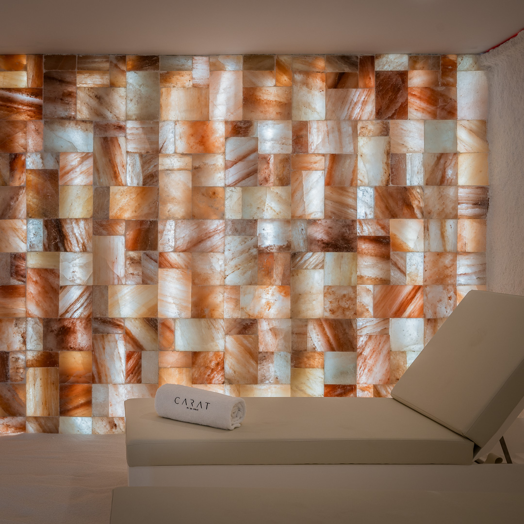 Sala de relax con camillas y pared de sal iluminada en el residencial Carat, RH Privé.