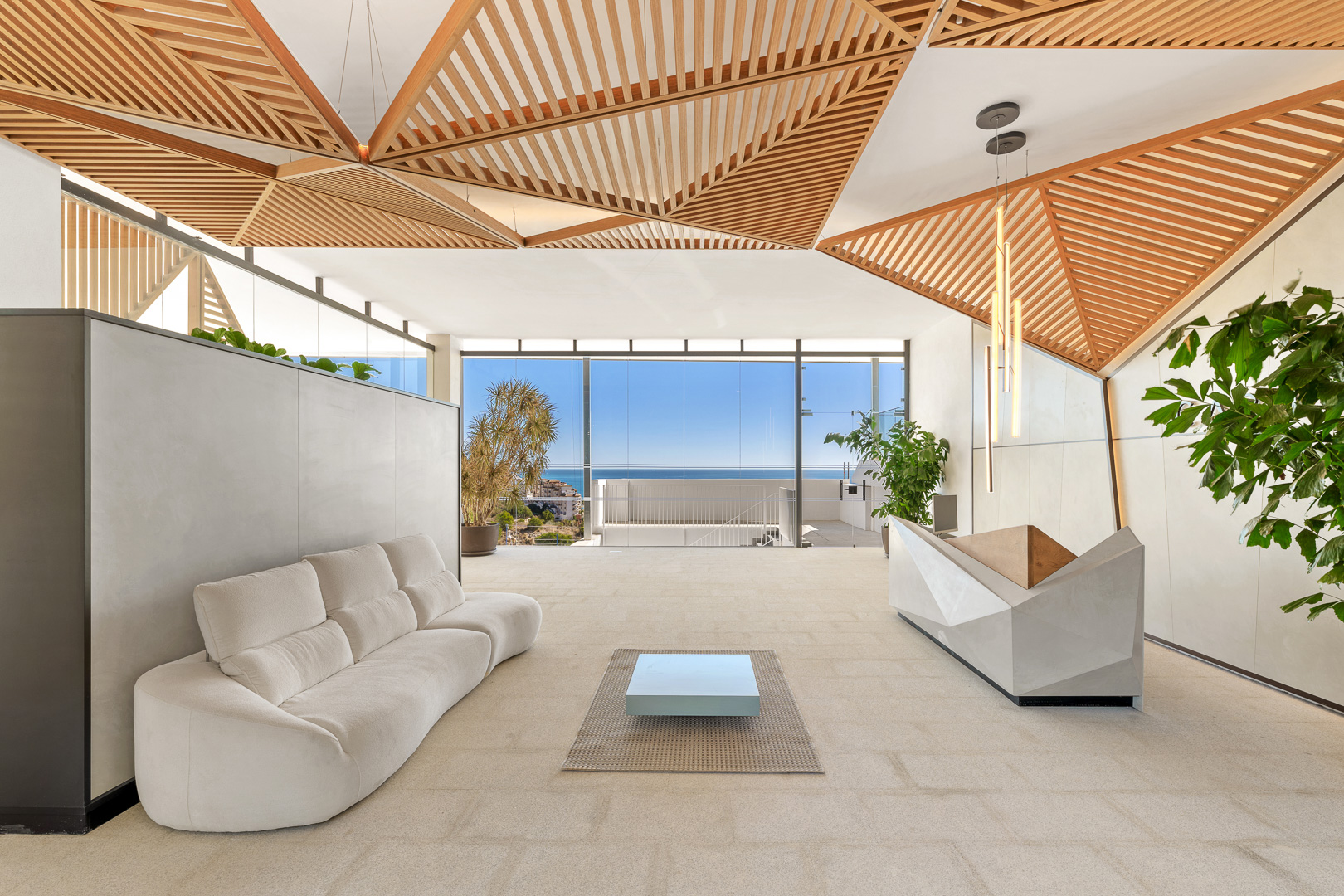 Zona de estar y hall con sofás y techo de madera en el residencial Carat.