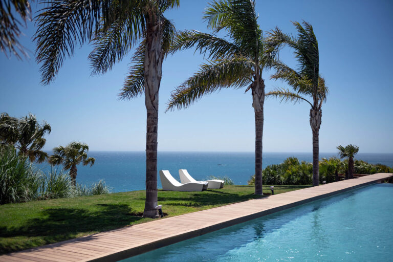 Piscina rodeada de palmeras con vistas panorámicas al mar en la reserva del Higuerón.