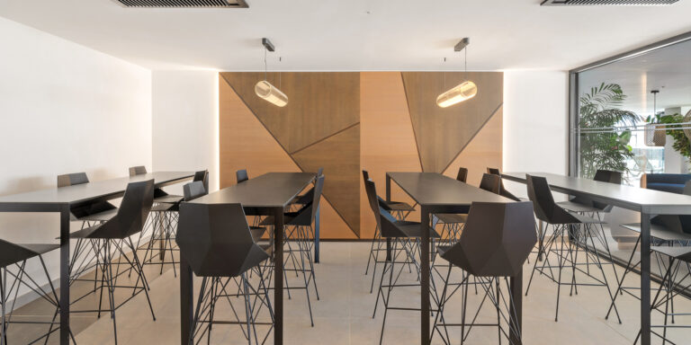 Área de coworking con mesas altas para compartir en zona común.