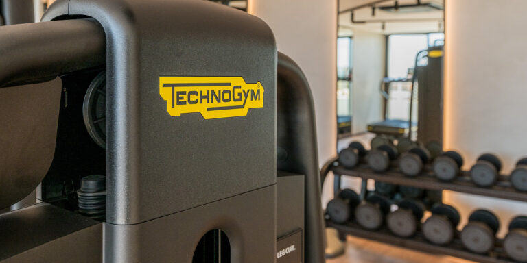 Máquina Technogym y pesas en el área de musculación del gimnasio RH Carat.