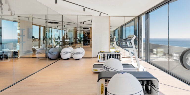 Gimnasio con grandes ventanales y vistas al mar en el residencial RH Carat.