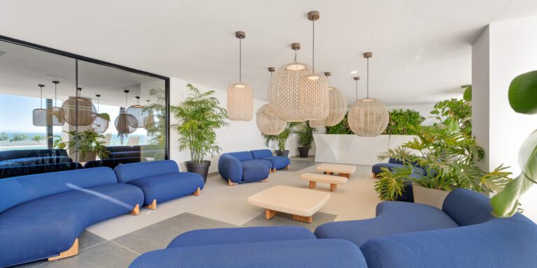 Lounge de coworking con sofás, iluminación decorativa y elementos vegetales.