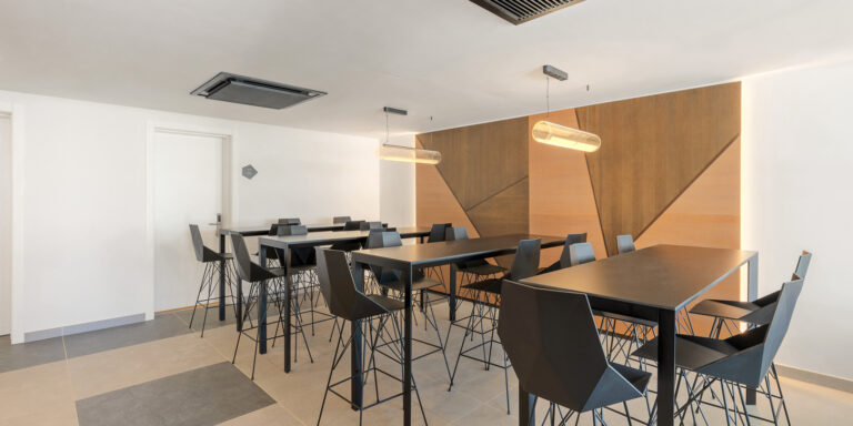 Sala de coworking con mesas de trabajo, asientos modernos y paneles decorativos de madera.