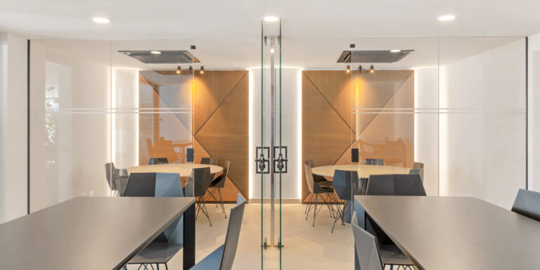 Espacio de coworking acristalado con mesas de trabajo y sillas.