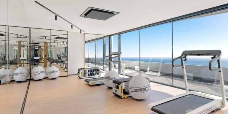 Zona de cardio con cintas de correr y vistas panorámicas al mar en RH Carat.